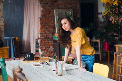 Portrait of smiling young woman sitting on table