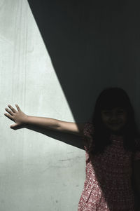 Midsection of woman with arms raised against wall