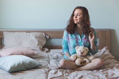 Portrait of young woman sitting on bed