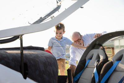 Grandson and grandfather inside airplane at airfield