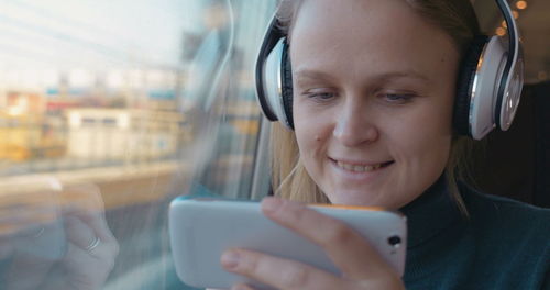 Portrait of smiling woman using mobile phone in bus