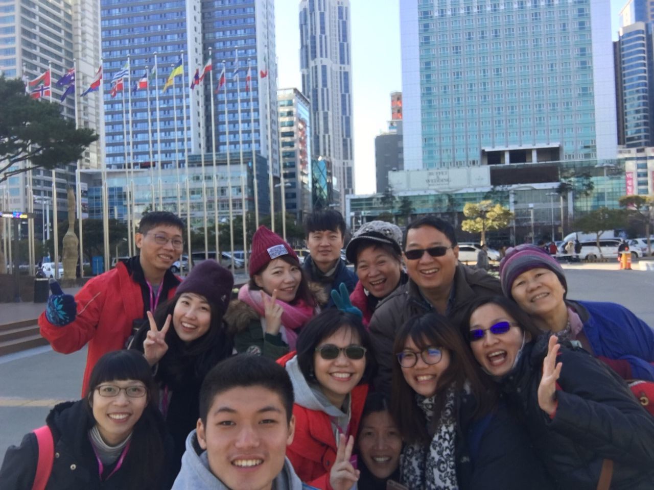 portrait, looking at camera, city, young women, young adult, smiling, large group of people, real people, lifestyles, happiness, women, building exterior, standing, outdoors, city life, architecture, adults only, crowd, cheerful, togetherness, day, men, adult, people, skyscraper, sky