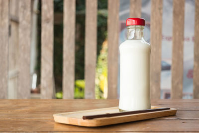 Close-up of milk bottle with straw in tray on table