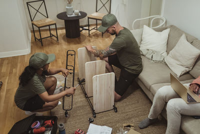 High angle view of male and female coworkers assembling rack by customer living room