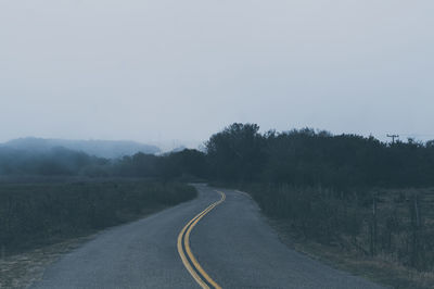 Road by trees against sky