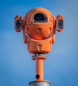 Low angle view of coin-operated binoculars against blue sky