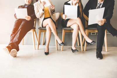 Low section of people sitting on chair