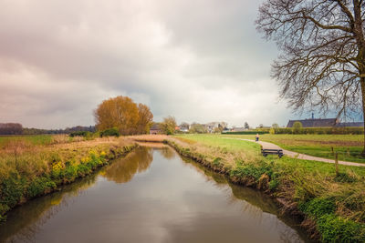 Scenic view of stream amidst field against sky