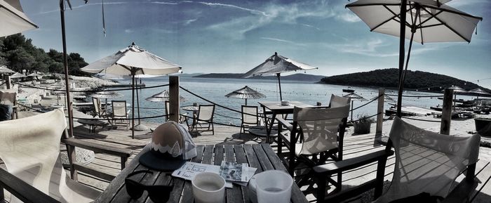 Chairs and tables at beach against sky