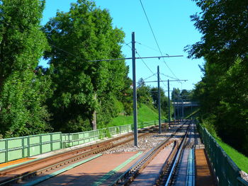 Railway tracks amidst trees against sky