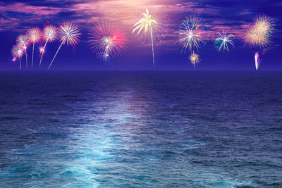 Firework display over sea at night