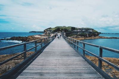 Pier on sea against cloudy sky