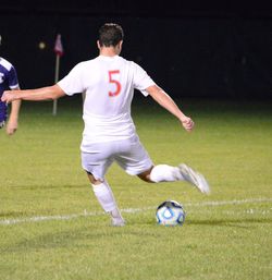 Rear view of man playing soccer ball on grass