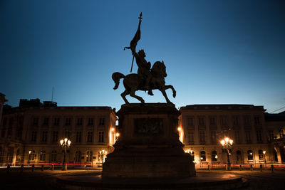 Statue in city at night