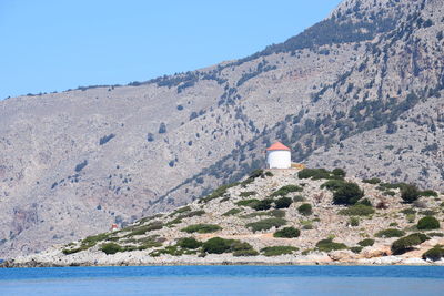 Lighthouse by sea against clear sky