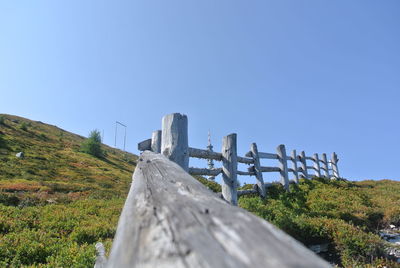 Low angle view of wooden structure on field against clear blue sky