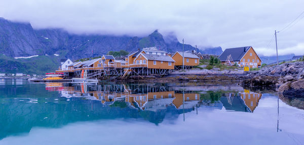 Buildings by lake against sky