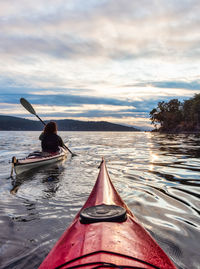 Man rowing boat in sea against sky