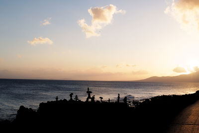 Silhouette people on beach against sky during sunset