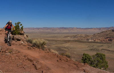 Dirt road in desert against clear sky