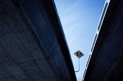 Low angle view of road sign board seen through flyovers against sky