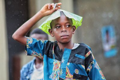 Boy covering head with leaf during rainy season