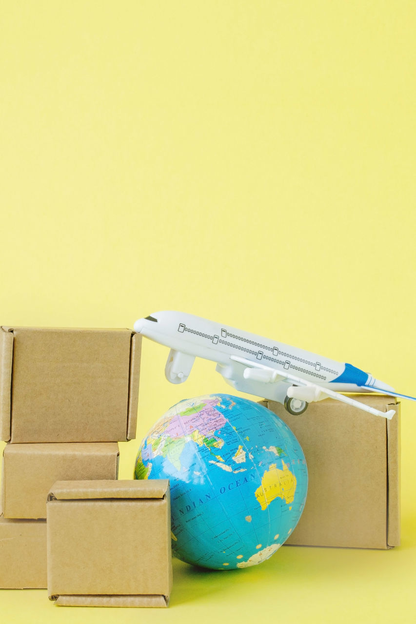 box, yellow, cardboard box, cardboard, copy space, globe - man made object, business, studio shot, indoors, colored background, no people, travel, container, packing, global business, carton, paper, map, moving house