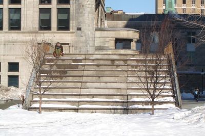 Person in snow against built structure in winter