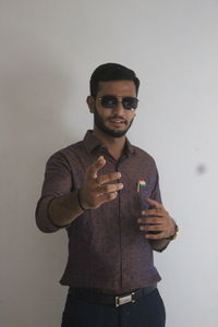 Young man using mobile phone standing against wall