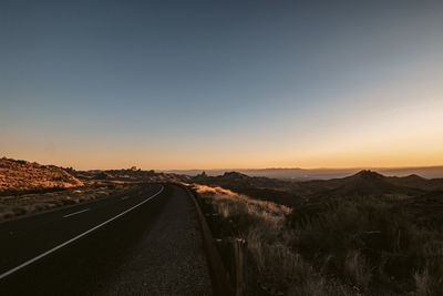 Road amidst landscape against clear sky during sunset