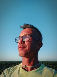 Man wearing eyeglasses against clear blue sky