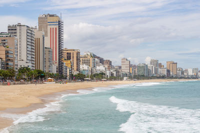 Buildings by sea against sky in city