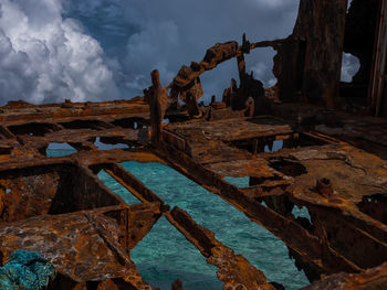 Abandoned rusted ship on shore against sky