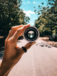 Close-up of hand holding lens against sky