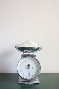 Close-up of clock on table against white background