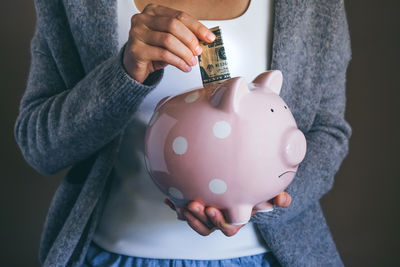 Woman putting bill in sad piggy bank. female saving money. economic crisis concept
