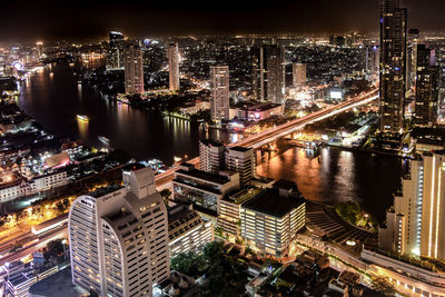 High angle view of illuminated buildings by river at night