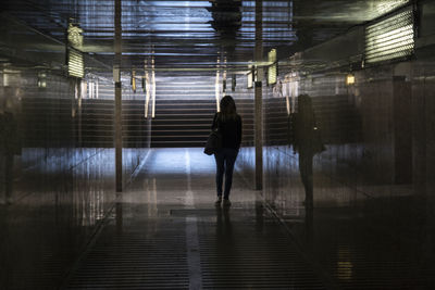 Rear view of woman walking in illuminated building