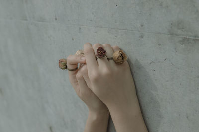 Cropped hands of young woman with rose shape rings on wall