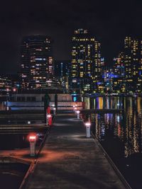 Illuminated city buildings against sky at night