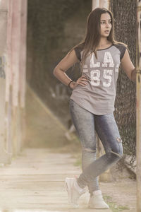 Teenage girl looking away while standing by fence