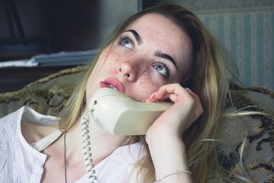 Woman looking away while talking over phone at home