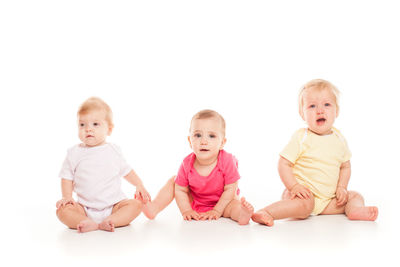 Portrait of cute baby boy sitting against white background