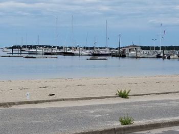 Sailboats moored at harbor against sky