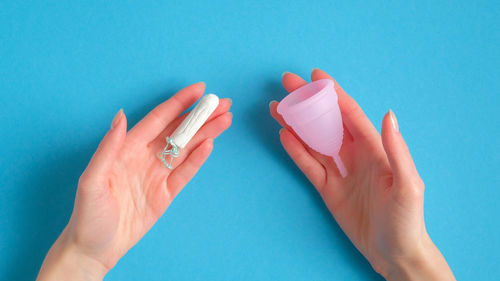 Close-up of hand holding blue over white background