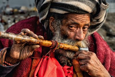 Close-up portrait of mature bearded man playing flute