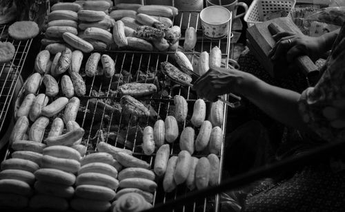 Cropped hand of woman roasting food on barbecue grill