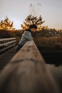 Side view of man standing by railing against sky