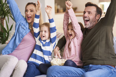 Happy friends sitting on sofa at home