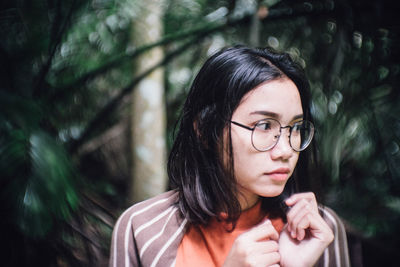 Close-up of woman looking away against plants